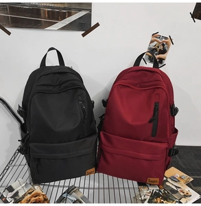 Detail of durable nylon backpacks in black and red with side buckles and logo label