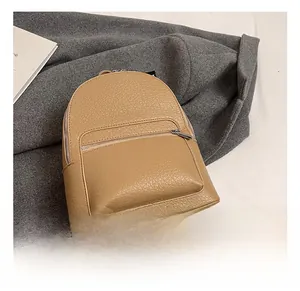 Detail of khaki leather mini backpack showing lychee texture and front zipper pocket