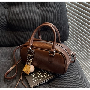 Détail d'un sac Boston en cuir ciré marron avec un pendentif de gant de baseball