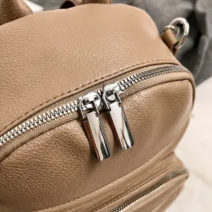 Detail show of polished silver dual zippers and pebble grain leather on a brown bag
