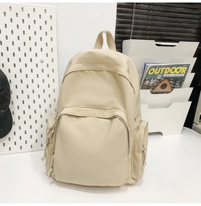 Détail d'un sac à dos minimaliste beige avec poches zippées et texture mate et lisse