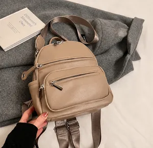 Detail showing beige PU leather mini backpack with silver zippers and fabric shoulder straps