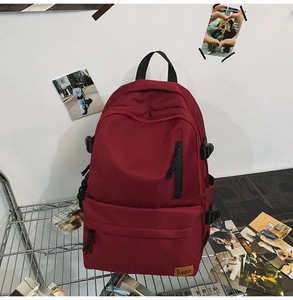 Detail view of burgundy waterproof backpack with front zipper and brand logo on mesh rack