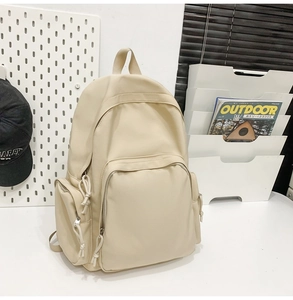 Détail d'un sac à dos en toile beige avec plusieurs poches et tirettes en cordon