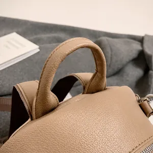 Detailed close-up of the brown lychee grain leather handle and strap craftsmanship