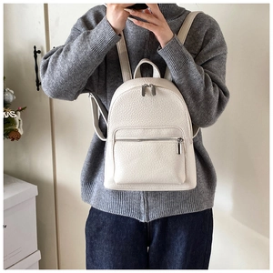 Close-up of a white lychee grain leather mini backpack showing texture and silver zippers