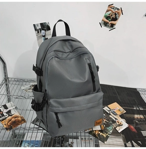 Close-up of a grey nylon backpack featuring multiple zippers and a leather logo patch