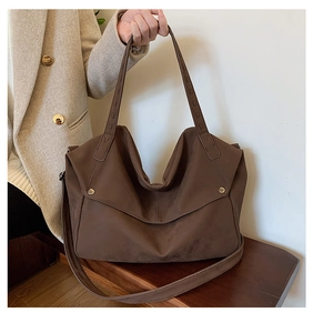 Μεγάλη vintage καφέ τσάντα tote με μεταλλικά πριτσίνια σε ξύλινο πάγκο