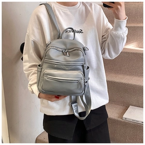 Detail of grey multi-pocket casual backpack worn by model on stairs in a minimalist style