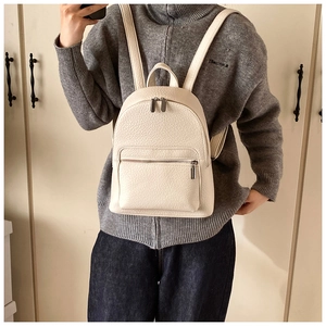 Detail shot of beige faux leather backpack with litchi texture and front zipper pocket
