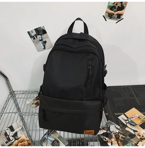 Detailed view of durable black nylon backpack with brand label and side adjustable straps