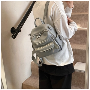 Detail of grey mini backpack featuring lychee grain texture and silver metal zippers