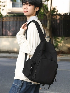 Sac à dos noir minimaliste grande capacité avec larges bretelles porté à l'extérieur