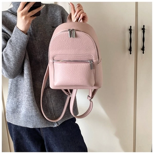 Detail view of pink pebbled leather mini backpack with silver zippers and top handle