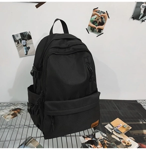 Detail of black waterproof nylon backpack featuring a leather brand patch on front