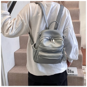 Rear view of a grey casual leather backpack with multi-zipper pockets on a model