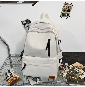 Detail of white nylon backpack featuring a leather brand logo and woven zipper pulls