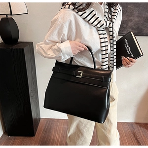 Detail of elegant black leather handbag with gold hardware shown in professional setting