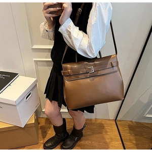Detailed side view of vintage brown leather tote bag with buckle and long shoulder strap