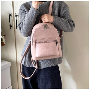 Detail of pink pebbled leather mini backpack showing metallic zippers and strap texture
