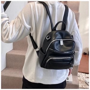 Back view of a woman wearing a black mini faux leather backpack with adjustable straps