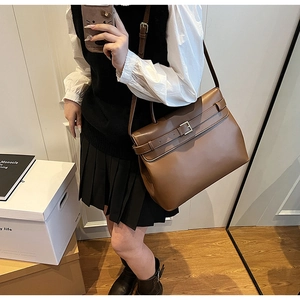 Brown vintage flap shoulder bag with belt buckle detail shown as a crossbody wear
