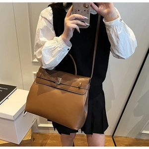 Brown leather handbag with silver hardware and shoulder strap shown in a full-length shot