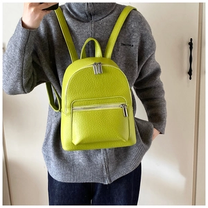 Detailed view of neon green lychee texture leather backpack worn on a gray sweater