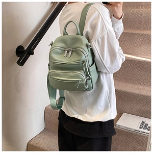Detail of mint green small textured backpack showing side pocket and metal zippers