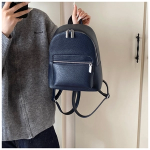 Detailed macro view of the navy blue lychee textured leather backpack and silver metal zippers