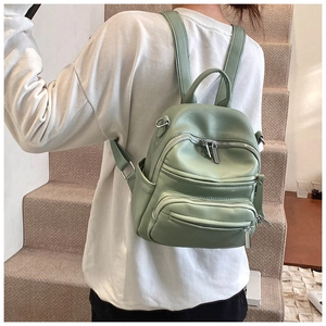 Detailed back view of a bean green mini PU leather backpack worn by a model in a minimalist setting