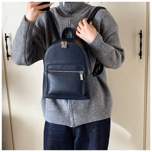Detail of dark blue leather backpack with litchi texture on a female model