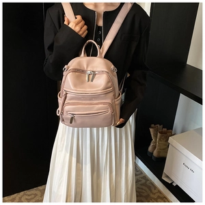 Close-up of a pink faux leather backpack with litchi texture and silver zipper details
