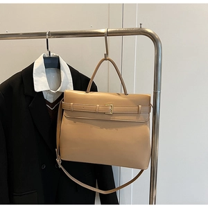 Minimalist beige structured briefcase bag hanging with a black suit for office look