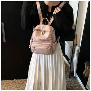 Detailed close-up of a pink mini faux leather backpack shown worn by a person