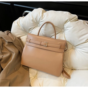 Detail of vintage khaki tote bag with buckle and handle on white quilted background