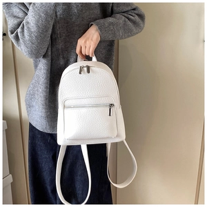 Close-up of white pebble grain mini backpack with silver zipper and slim leather straps