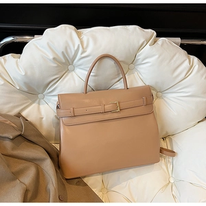 Detail of khaki leather briefcase with gold hardware on a white leather chair