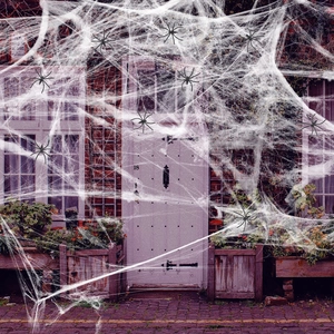 Close-up of stretchy white faux spider web with black plastic spiders on a brick house