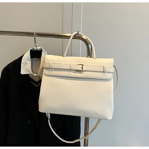 Close-up of ivory leather briefcase with slim strap, metal buckle and top handle detail