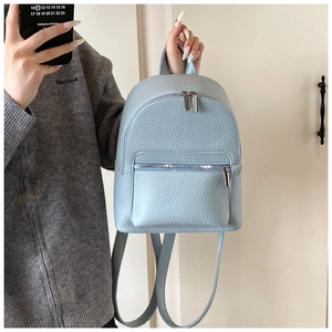 Detail of light blue mini backpack with lychee grain texture and silver zippers