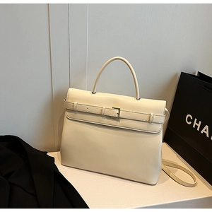 Detail view of cream leather handbag featuring gold metal buckle and smooth matte finish