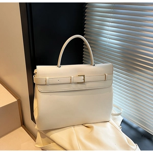 Detail of a minimalist beige leather handbag with metal buckle and natural window light