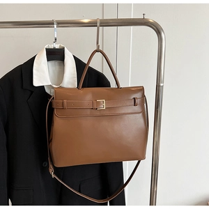 Close-up of brown leather briefcase on hanger with blazer for professional styling
