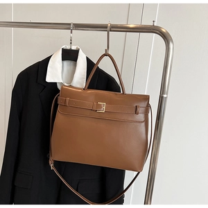 Detail of brown faux leather tote bag with decorative buckle strap and adjustable handle