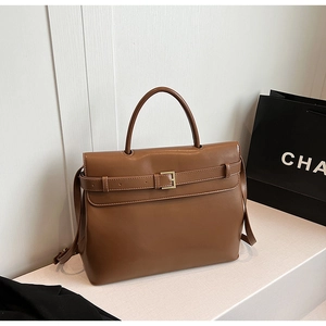 Close-up of brown leather handbag with gold hardware and removable shoulder strap