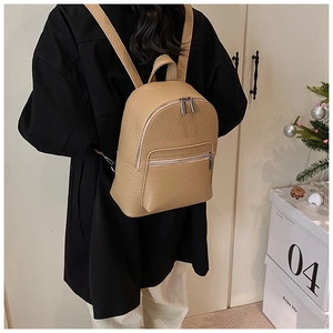 Close-up of khaki faux leather backpack with litchi texture and silver zipper details