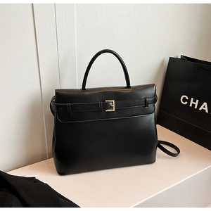 Detail of minimalist black leather handbag featuring golden metal buckle and belt detail
