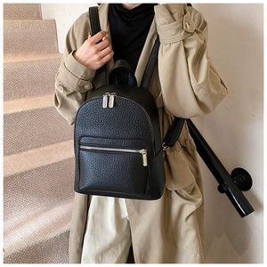 Close-up of black lychee grain leather backpack featuring polished silver metal zippers