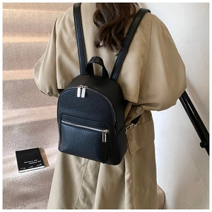 Litchi texture leather backpack detail with silver zippers on a model in trench coat